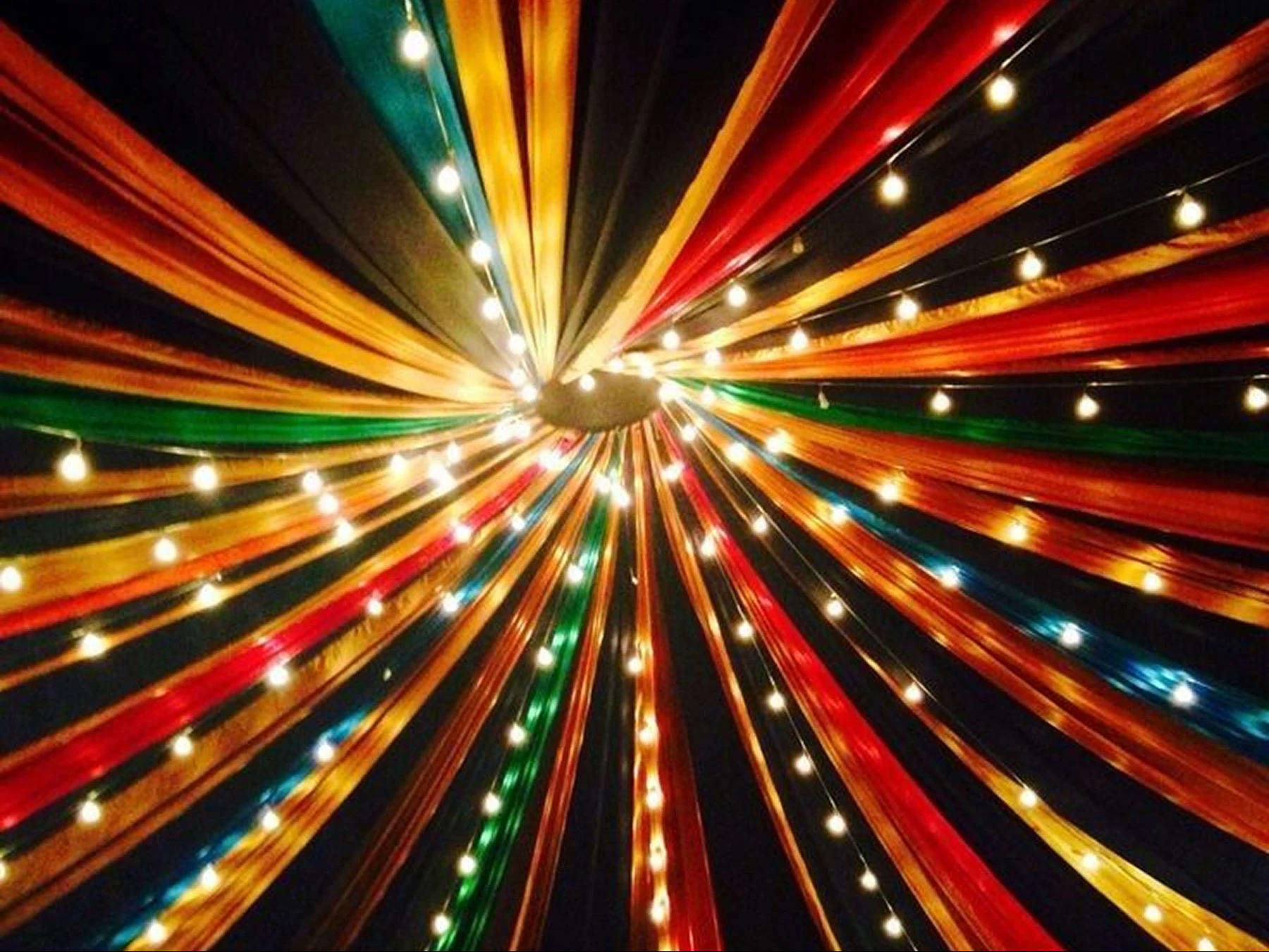 A canopy of colourful fabric and warm festival lights